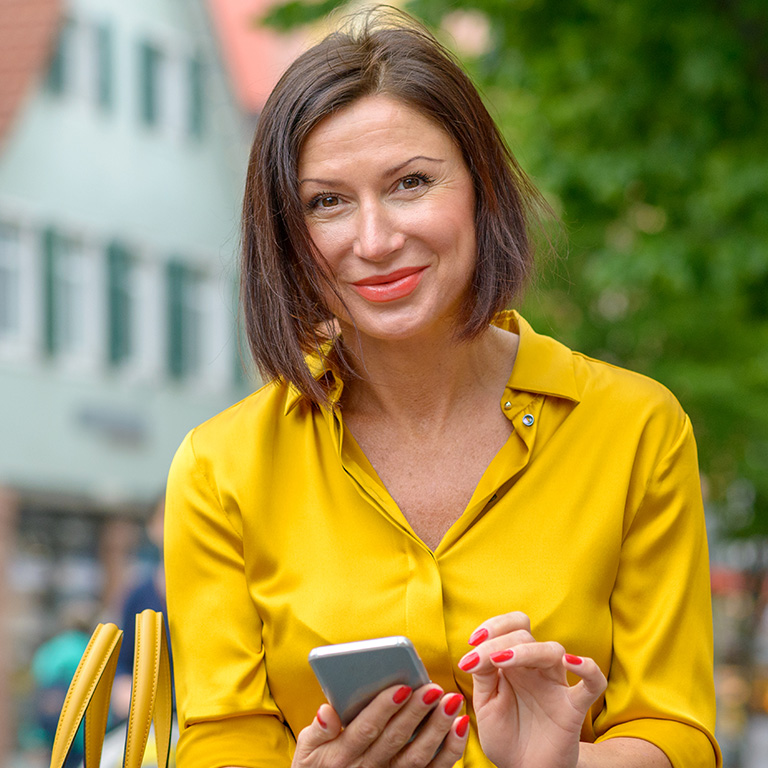 Vrouw in gele blouse met haar mobiel