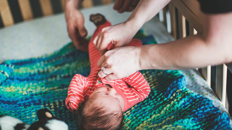 Baby wordt aangekleed door ouders