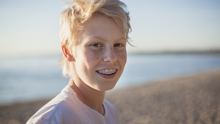 Jongen met beugel op het strand