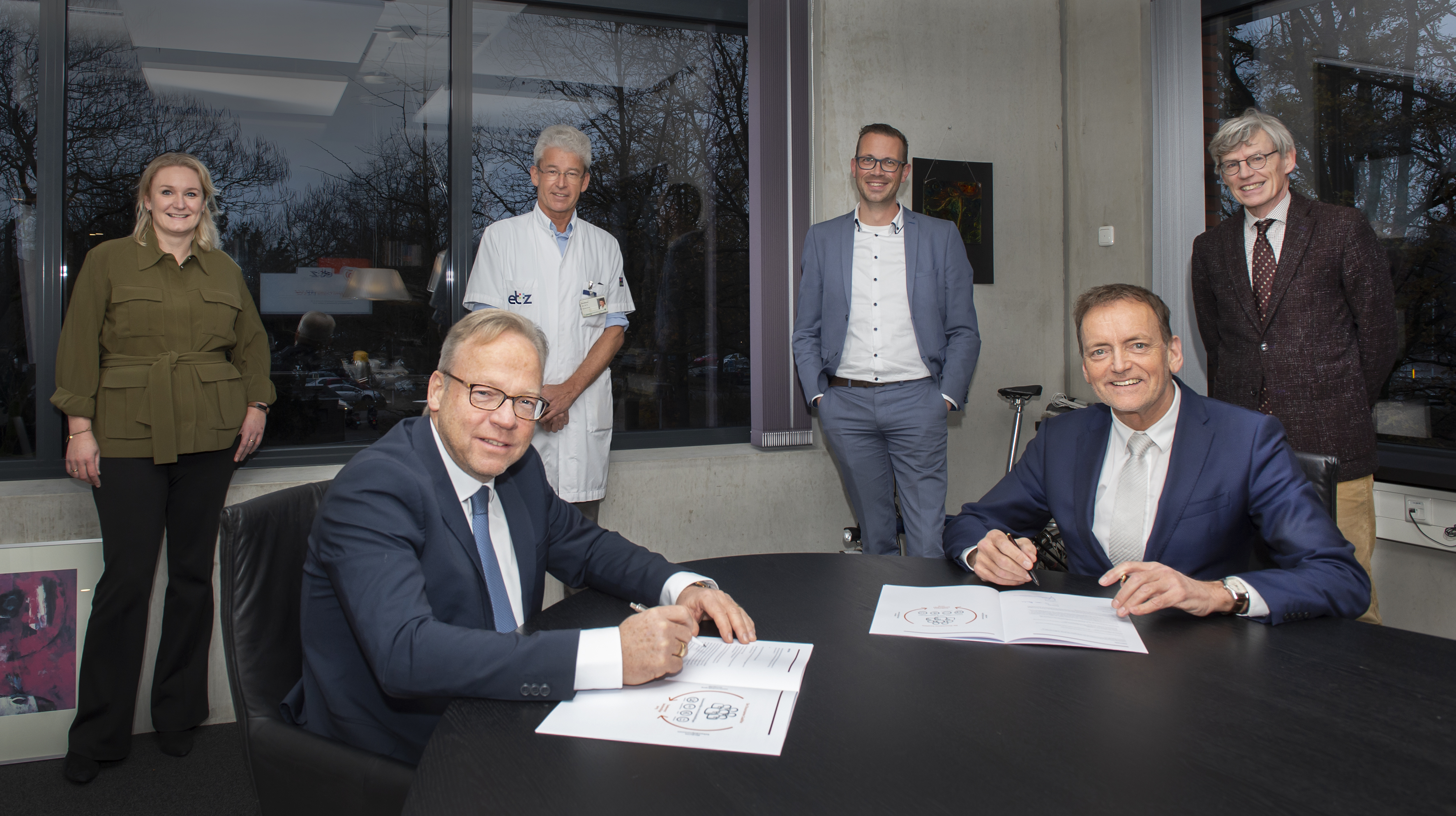 CZ-directeur Joël Gijzen (l.) en ETZ-bestuurder Gerard van Berlo tekenen de overeenkomst. Op de achtergrond kijken (v.l.n.r.) Angelique Bonte - Van Rooijen (kwartiermaker Duurzame Coalities bij CZ), Focco Boekkooi (gynaecoloog en voorzitter Medisch Specialistisch Bedrijf) en ETZ-bestuursvoorzitter Bart Berden toe.