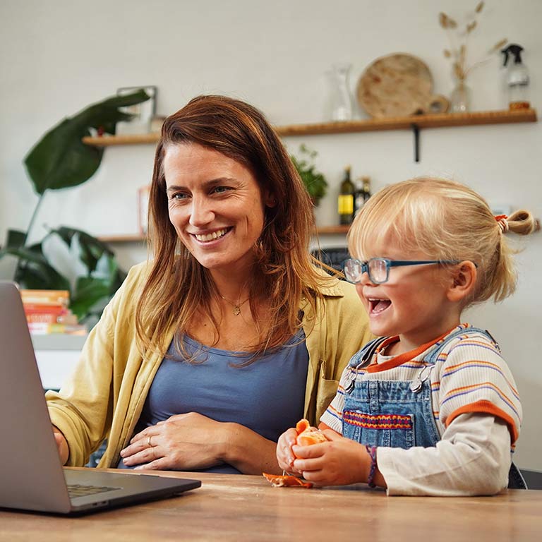 Mevrouw met meisje lachend achter de laptop