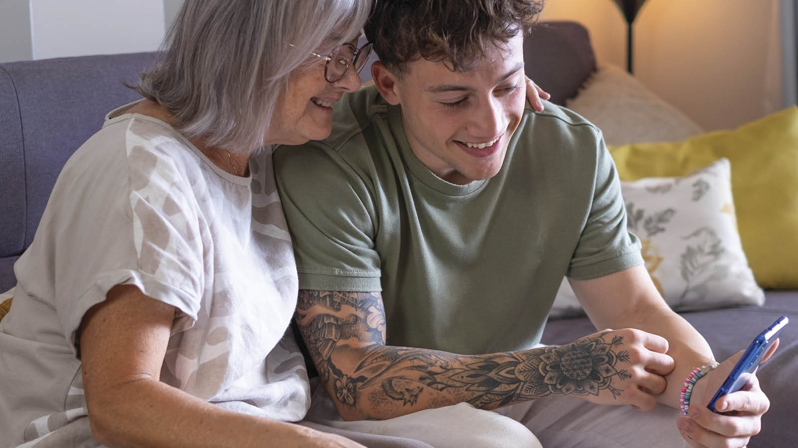 Twee personen kijken lachend op de mobiele telefoon