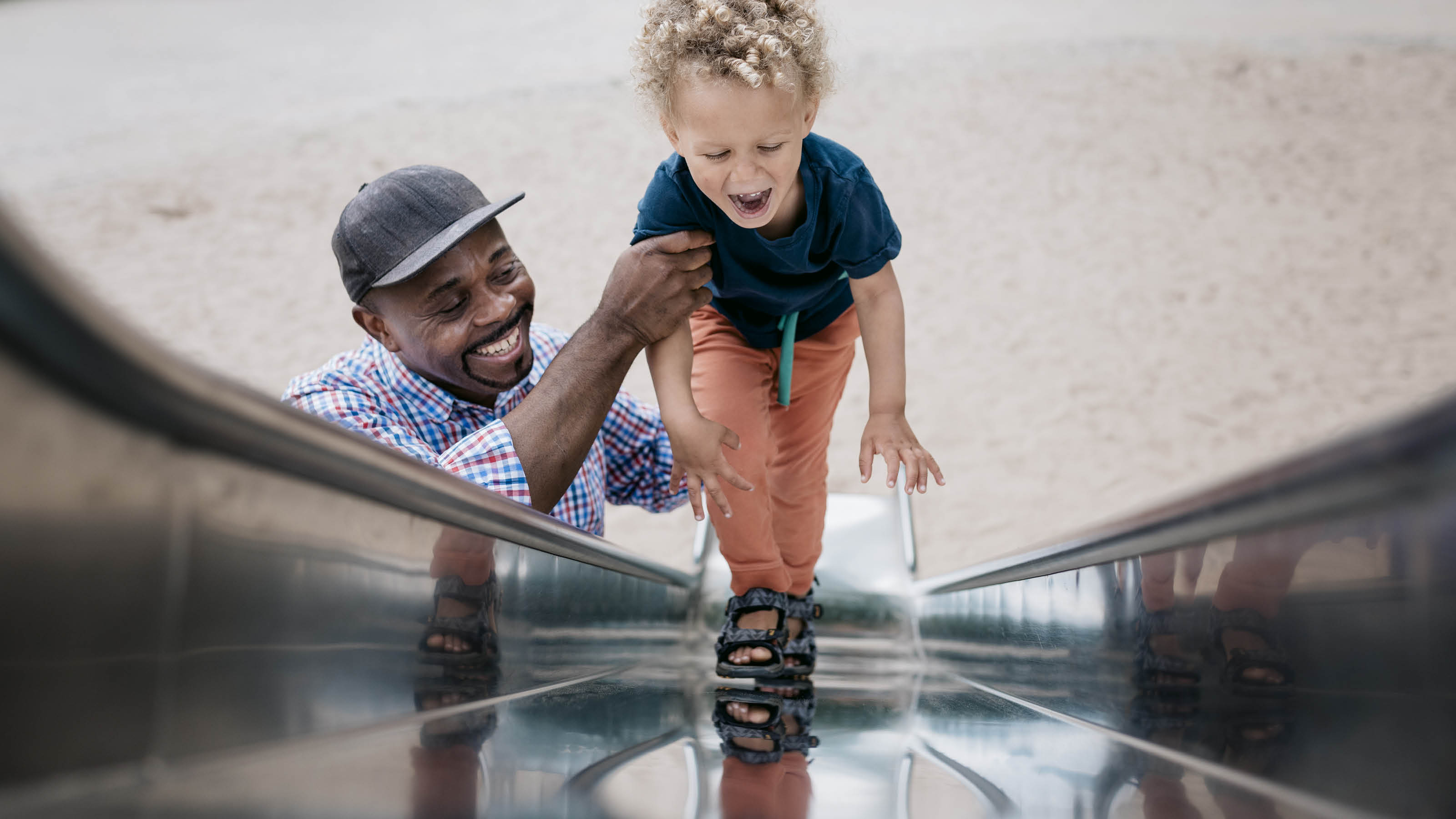 Man en kind bij de glijbaan