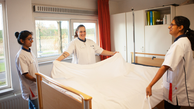 Drie vrouwen maken een bed op