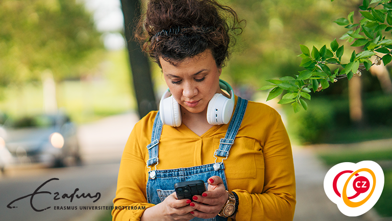 Vrouw met koptelefoon kijkt op haar telefoon