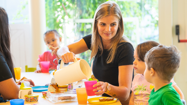 Kinderopvang - vrouw eet met kinderen aan tafel