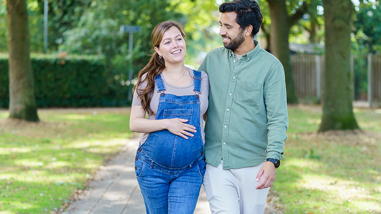 Zwangere vrouw loopt met man door het park