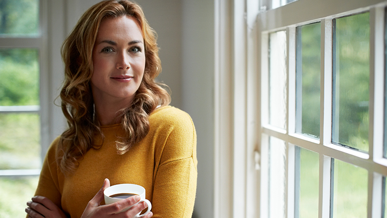 Vrouw met glas thee bij een raam