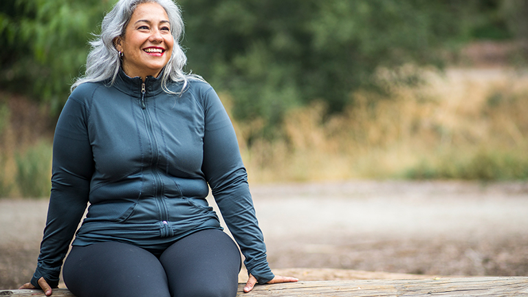 Vrouw zit op boomstam in bos