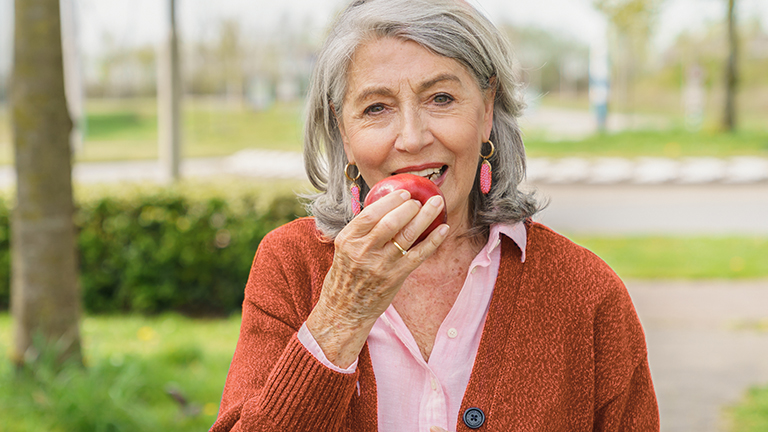 Oudere dame bijt in een appel