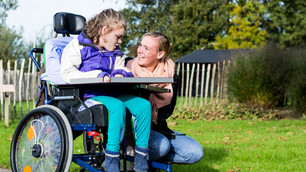 Meisje in rolstoel met begeleider