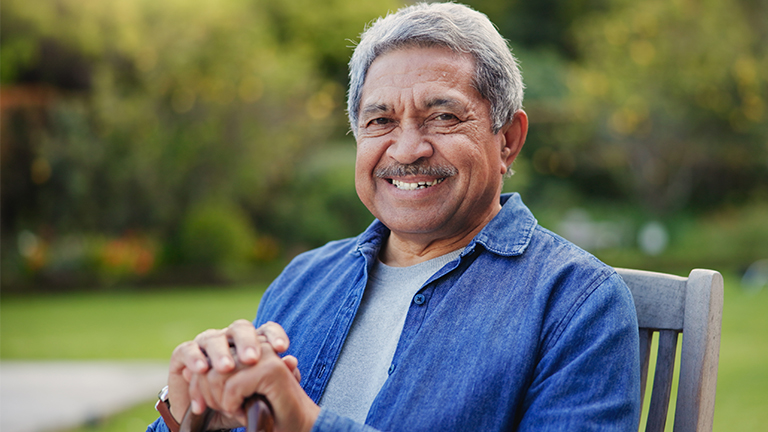 Man leunt op wandelstok en glimlacht