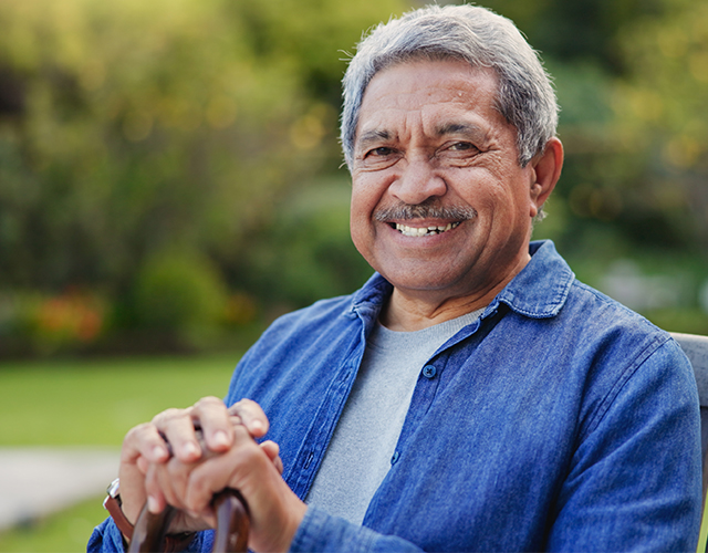 Man leunt op wandelstok en glimlacht