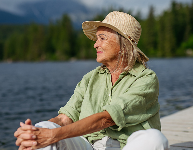 Vrouw zit in de zon aan het meer