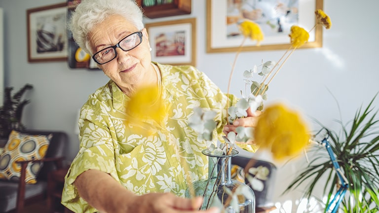 Elderly woman touching bouquet of flowers