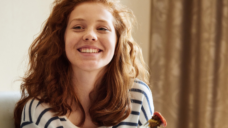 Een lachende vrouw gaat iets eten en is blij
