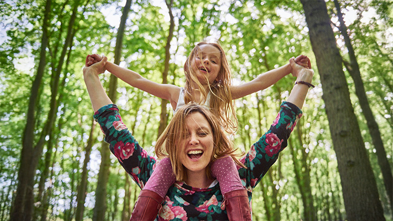Vrouw met kind op schouders in het bos